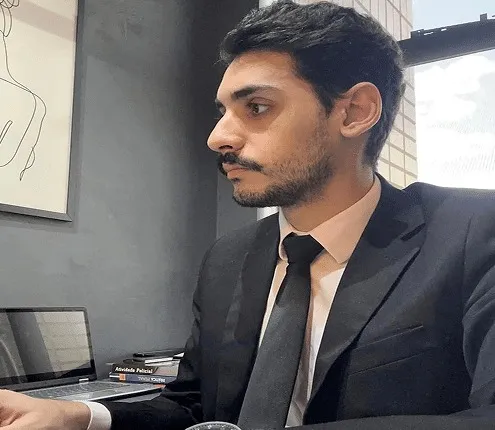 Advogado criminalista Guilherme Barros, de terno escuro e gravata, trabalhando no escritório em Belo Horizonte