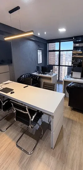 Sala de atendimento do escritório de advocacia criminal, com mesa, cadeiras e janela para o Centro de Belo Horizonte